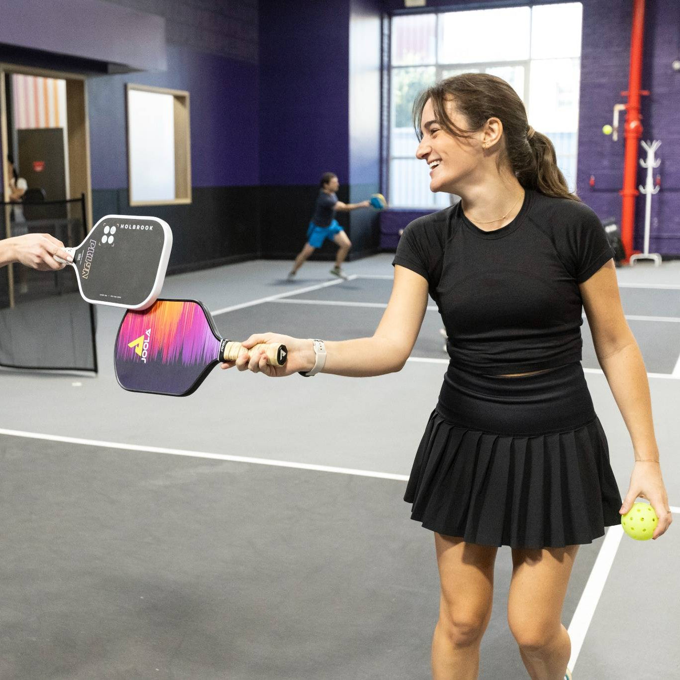 Two women playing pickleball in an indoor court