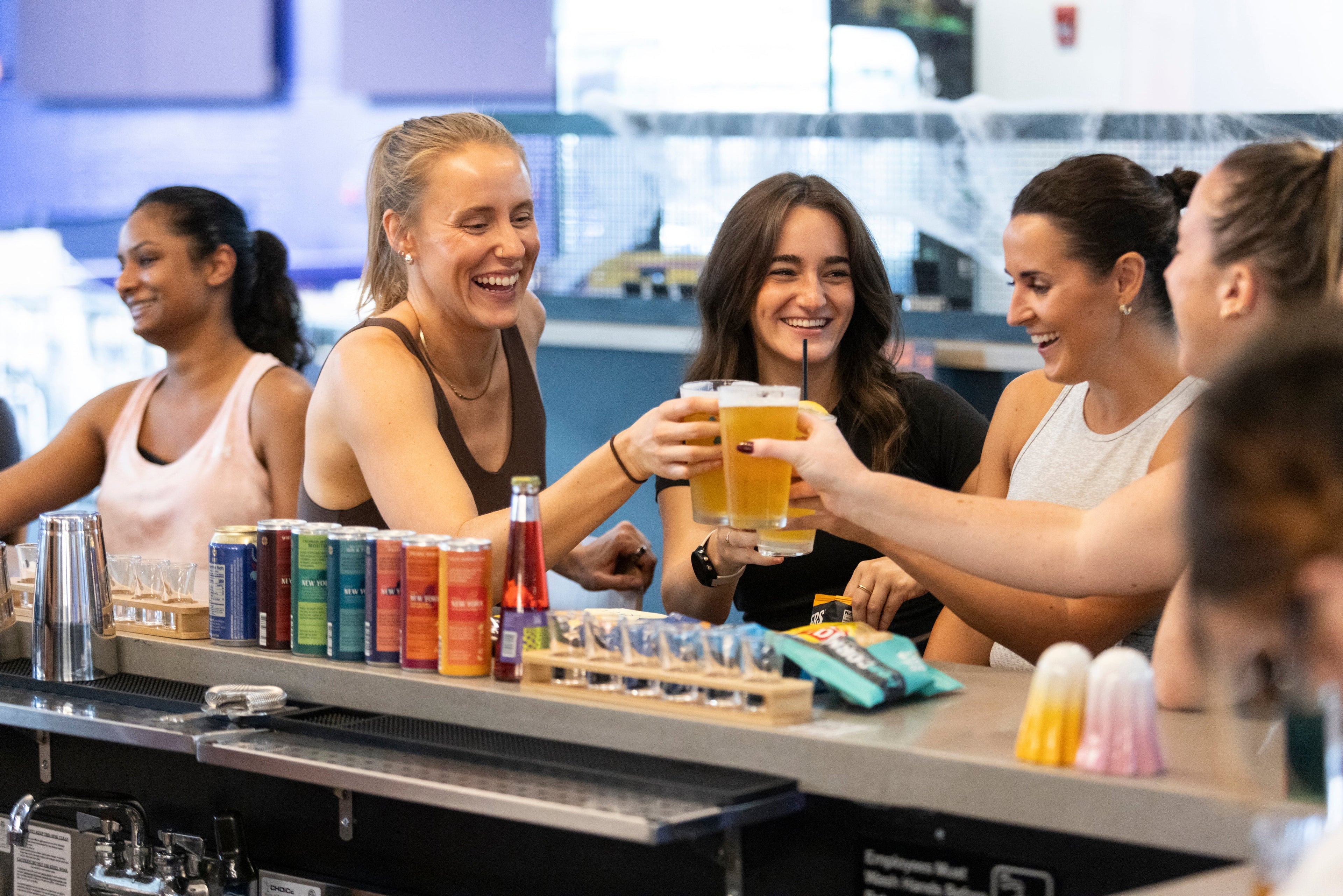Group of new friends enjoying drinks at a bar counter after pickleball with Silly Pickles