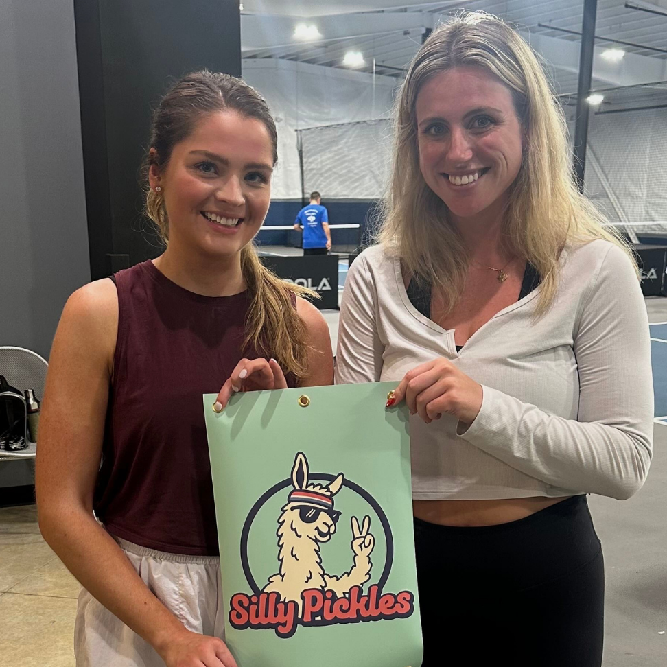 Two women holding a sign with &