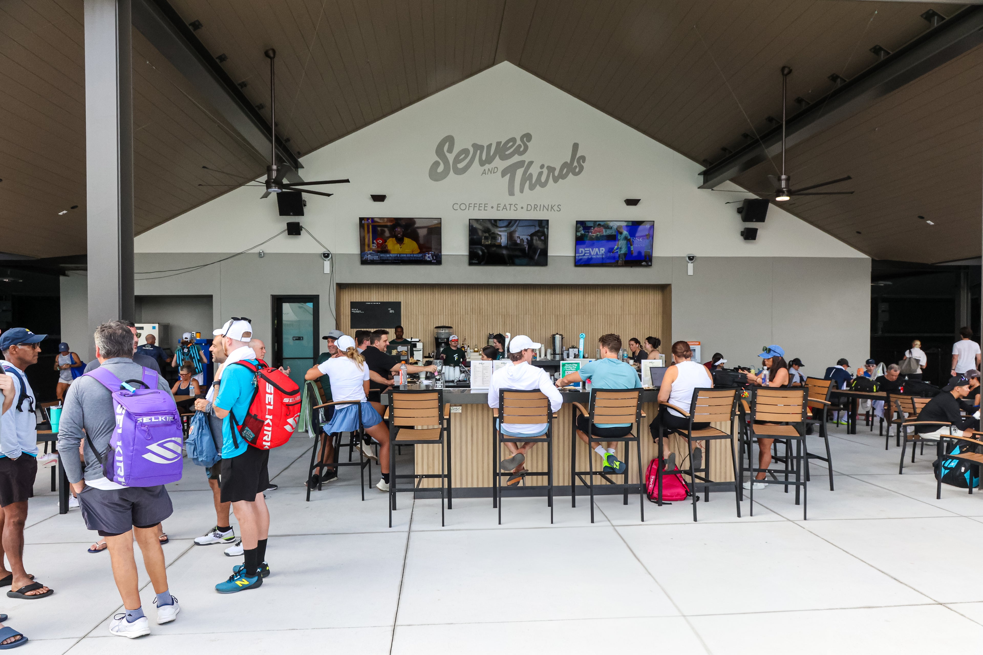 People gathered around tables in a covered outdoor area with &