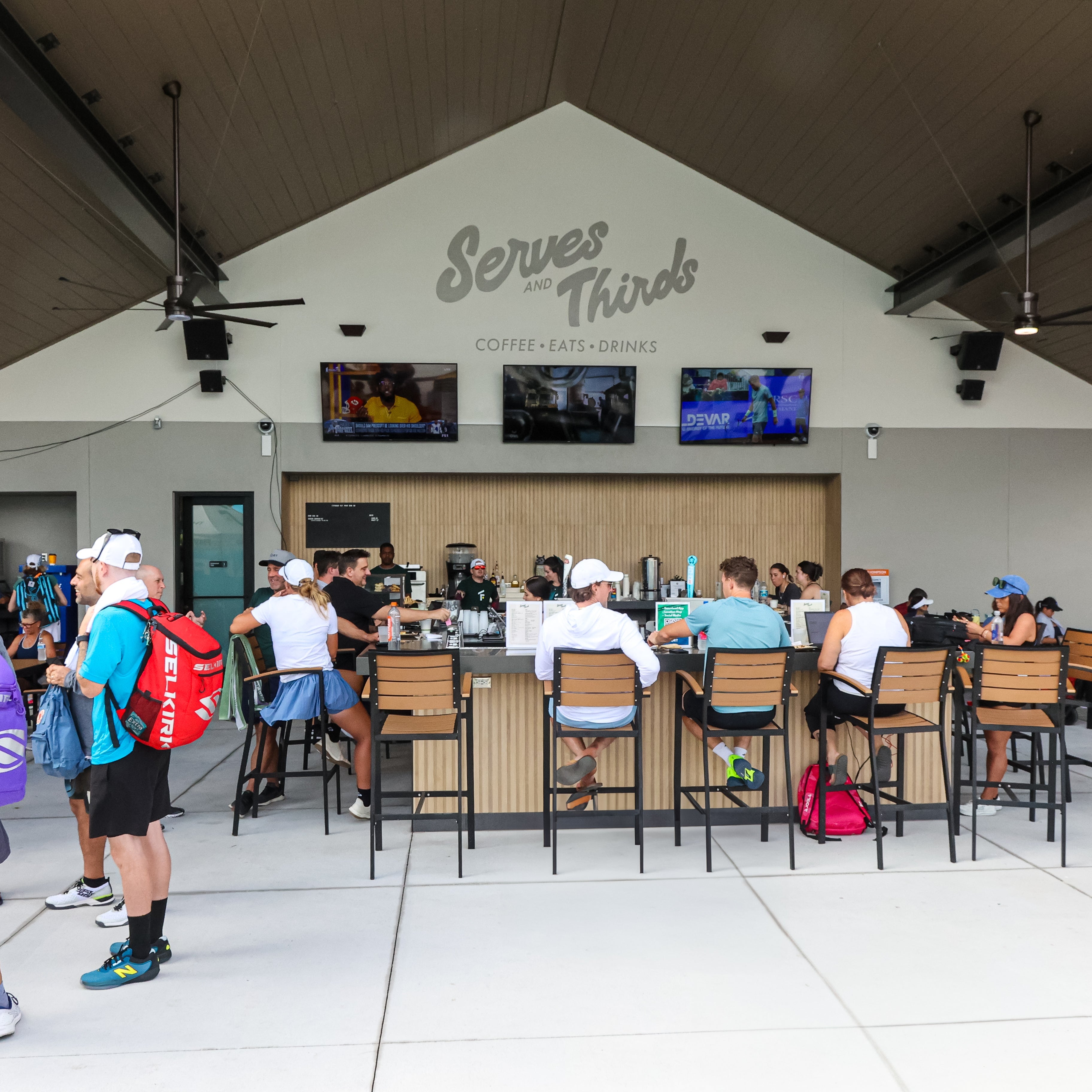 People gathered around tables in a covered outdoor area with &