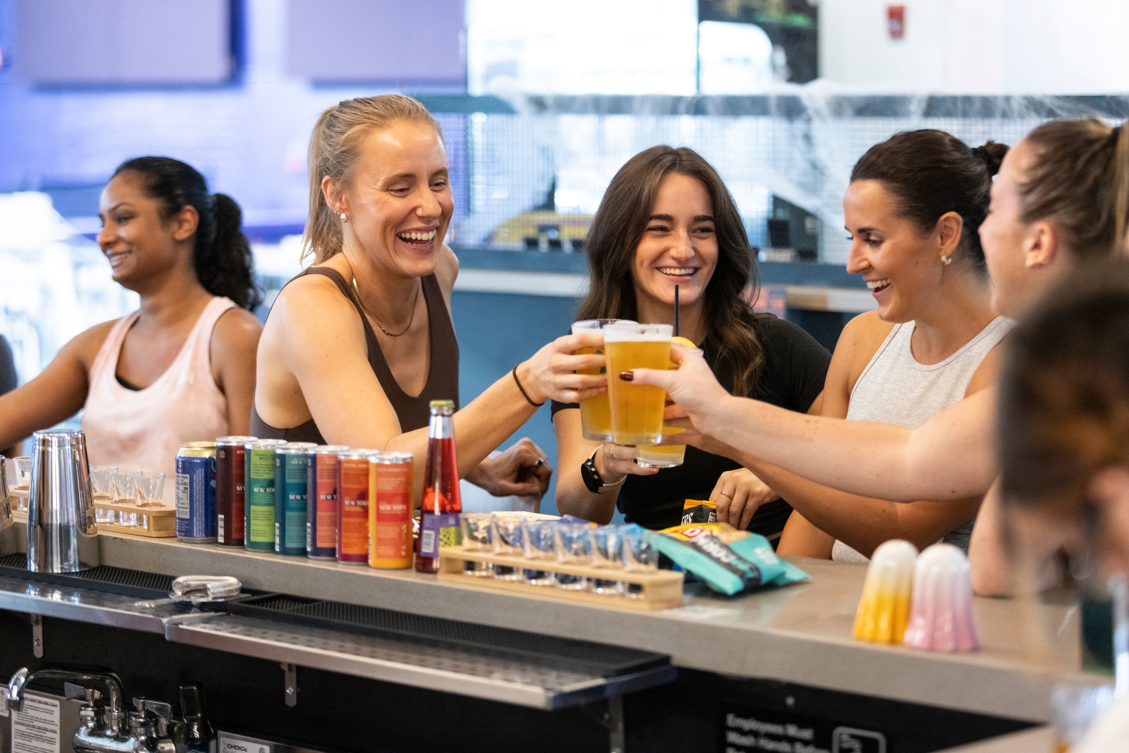 Group of new friends enjoying drinks at a bar counter after pickleball with Silly Pickles