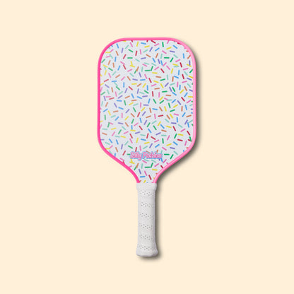 Silly Pickles pickleball paddle with colorful sprinkles pattern on a beige background