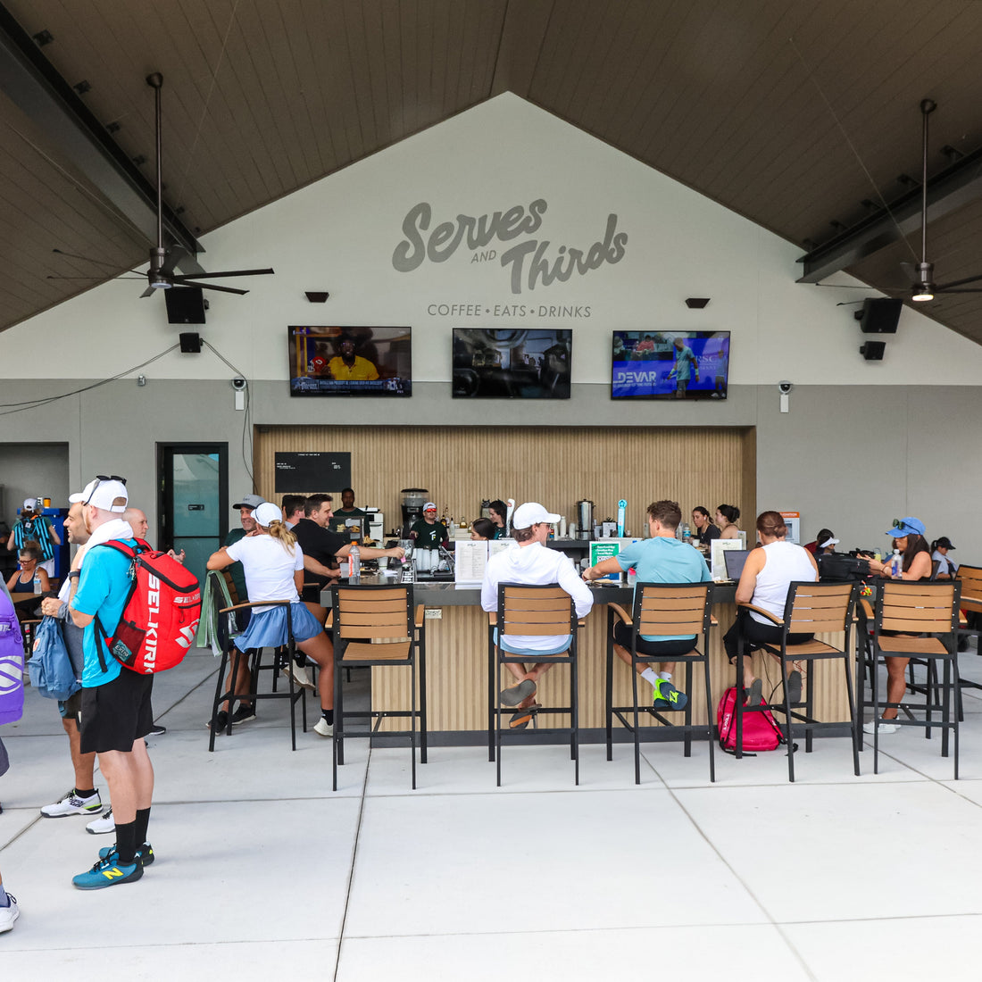 People gathered around tables in a covered outdoor area with &